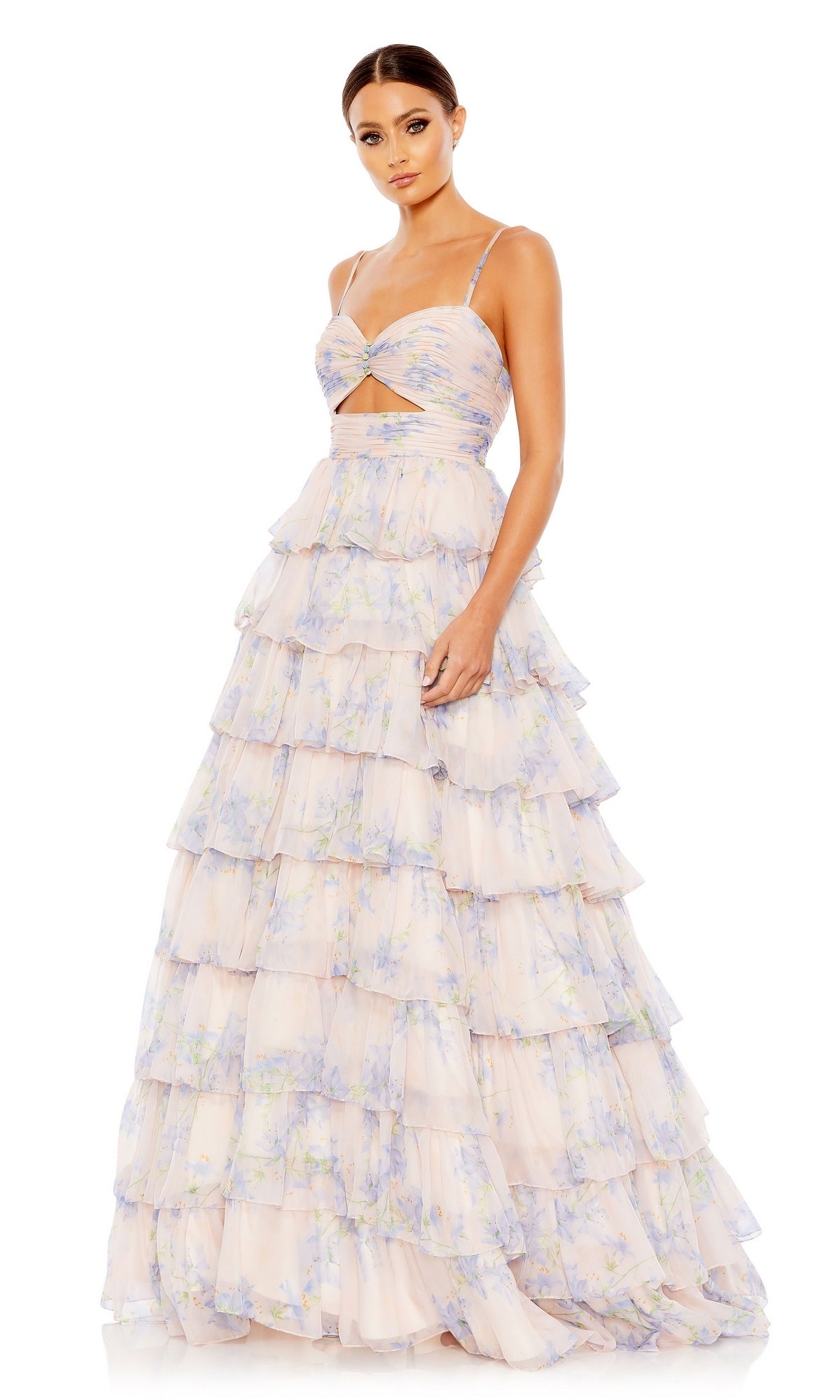 A woman wears the Violet Print Prom Ball Gown by Mac Duggal (67966), featuring pastel florals, spaghetti straps, a midriff cutout, and a ruffled tier skirt, standing against a white background.